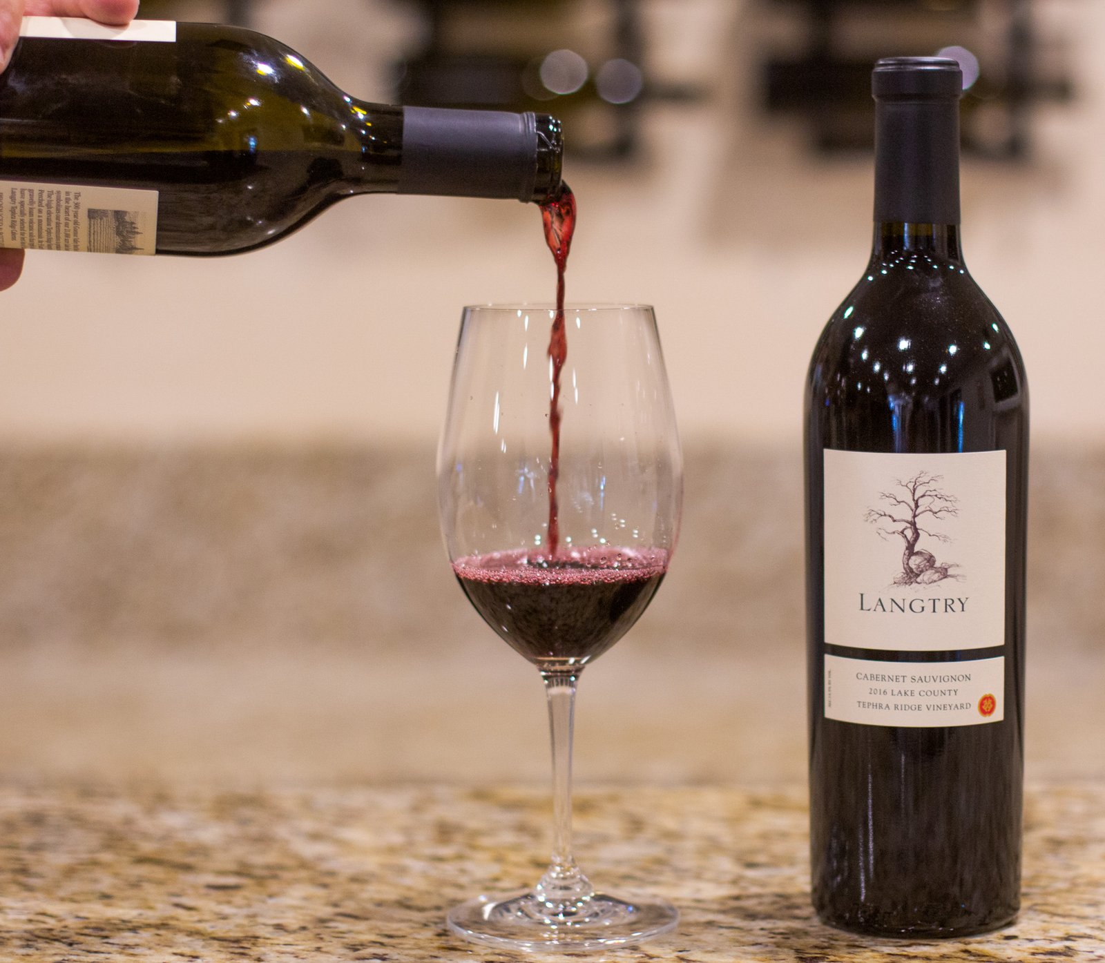 wine poured into a glass beside a wine bottle